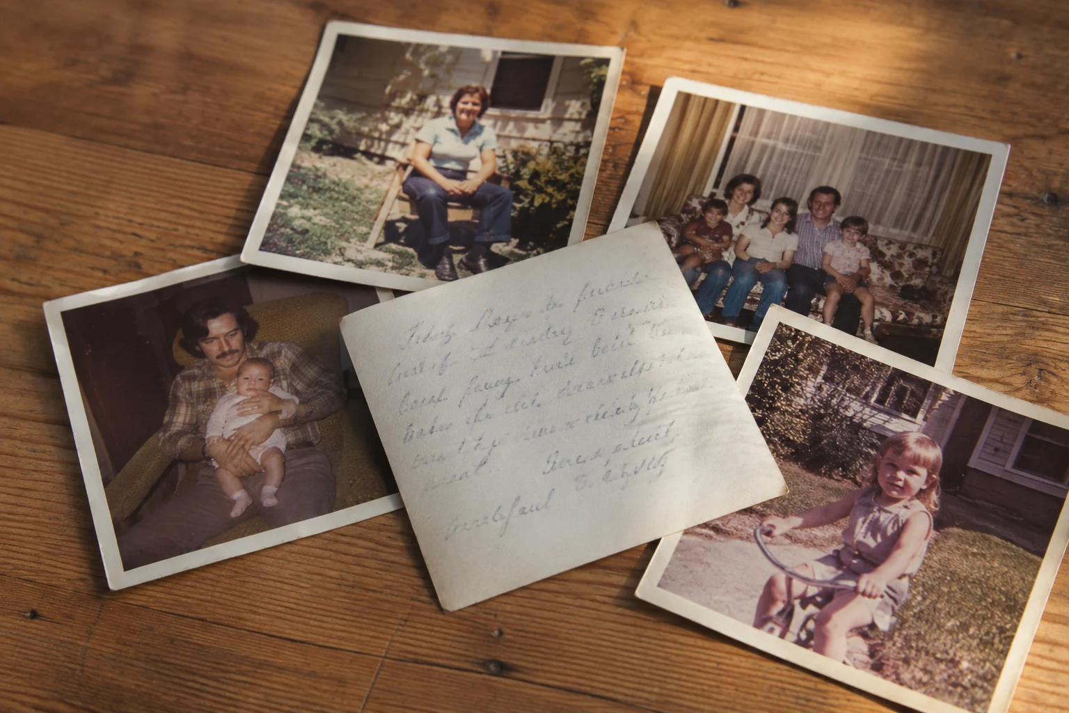 A stack of well-loved vintage photographs, including the handwritten back of a print